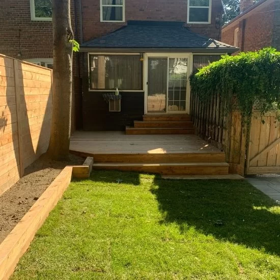 Backyard lawn with fresh sod installation, wooden deck steps, and prepared garden bed along fence, image by OAKS Home Services