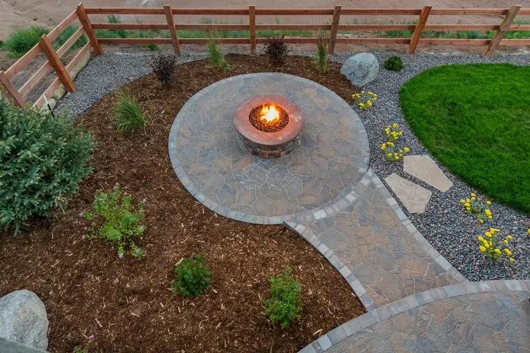 Stone fire pit patio with curved paver path and planting beds, image by OAKS Home Services
