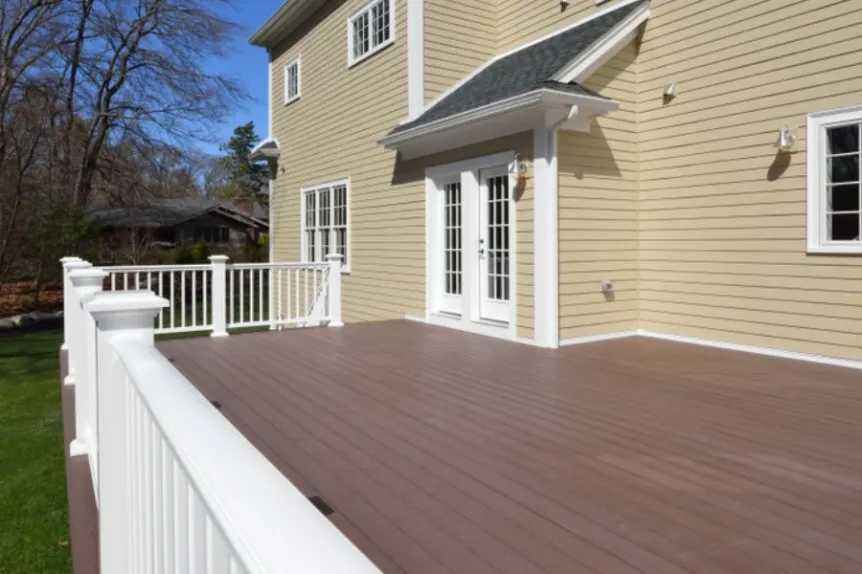 Spacious composite deck with white railing and backyard access doors