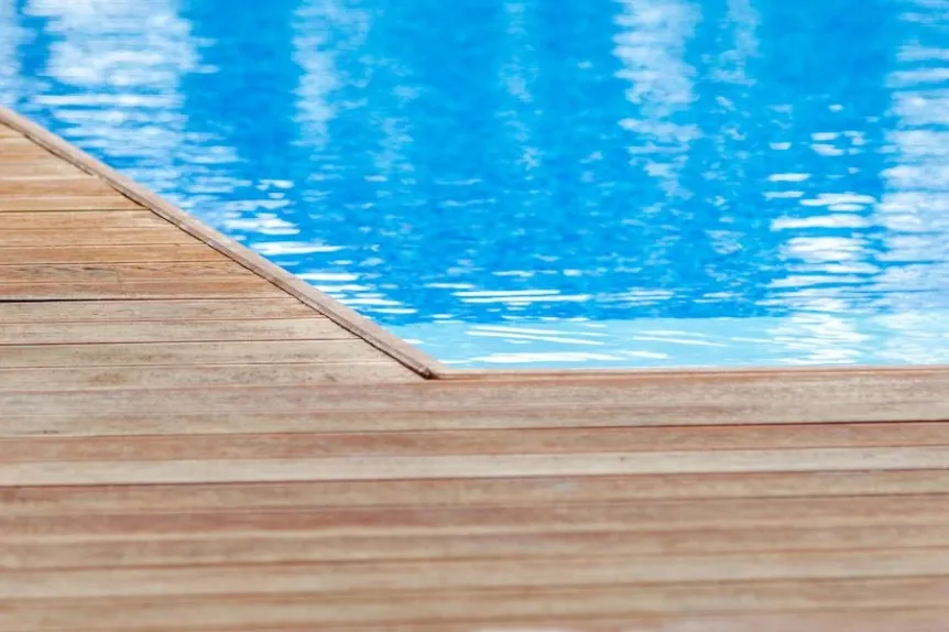Wood pool deck detail beside clear blue swimming pool