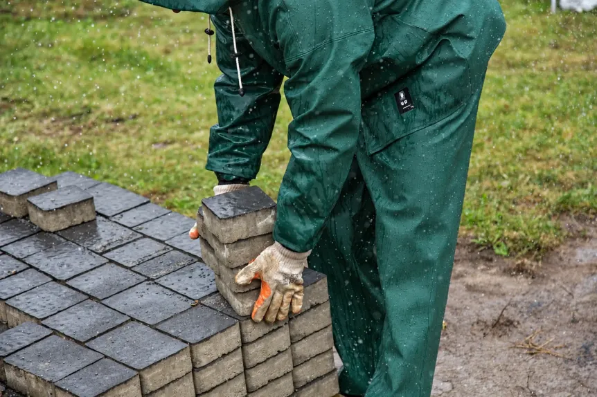 Gloved worker placing interlocking paving blocks by hand, photo Oakshs