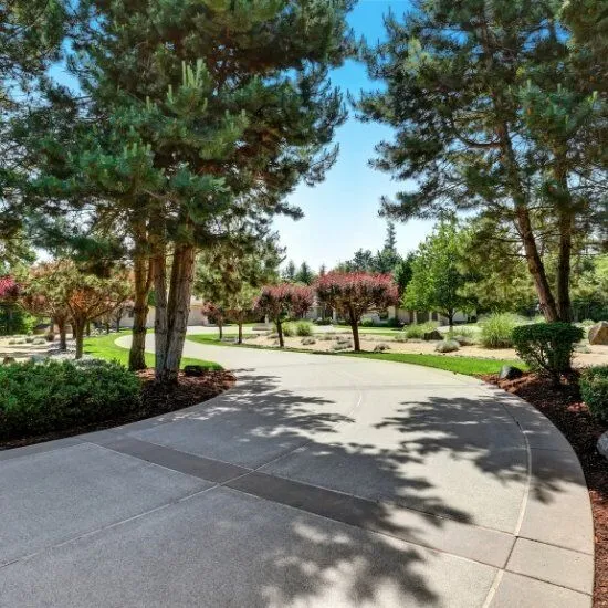 large-concrete-driveway Exposed aggregate concrete path winding through landscaped yard, photo by Oaks Home Services