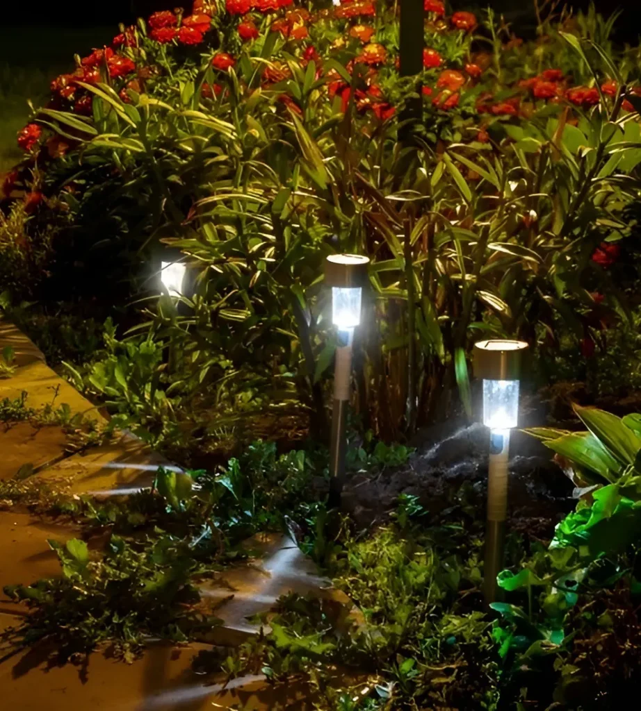 Solar garden path lights illuminating a flower bed at night