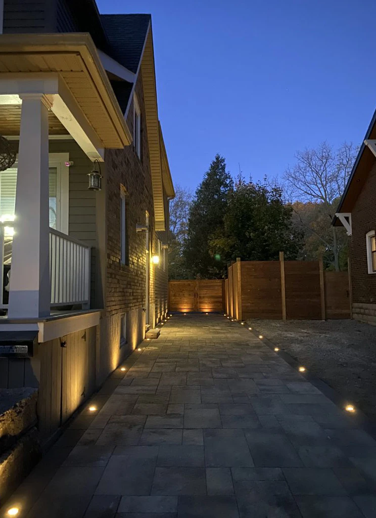 Exterior path lights illuminating a driveway with modern house siding