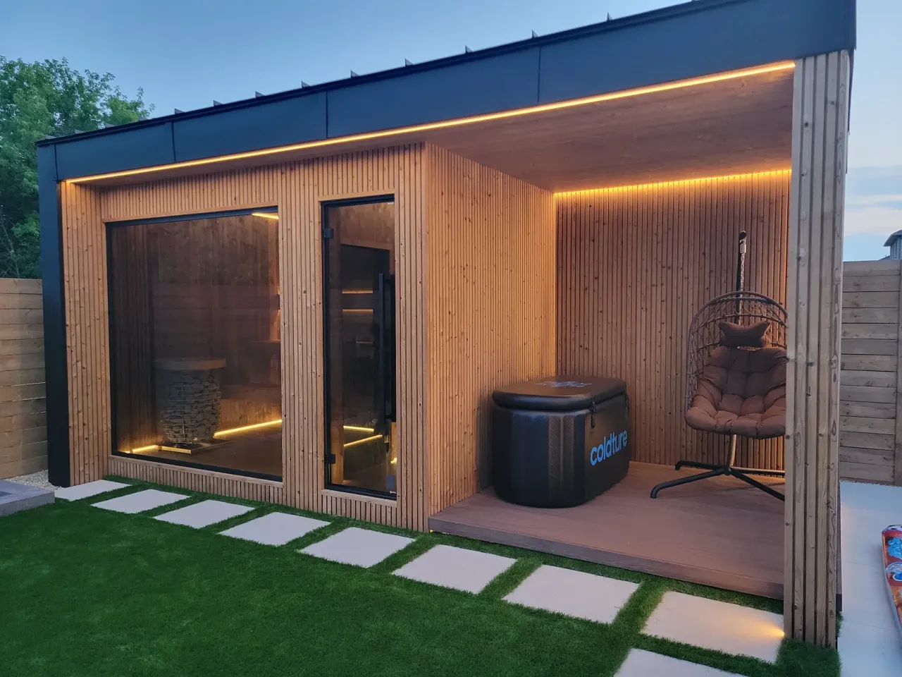 modern backyard sauna with wood cladding glass doors patio seating and ambient lighting