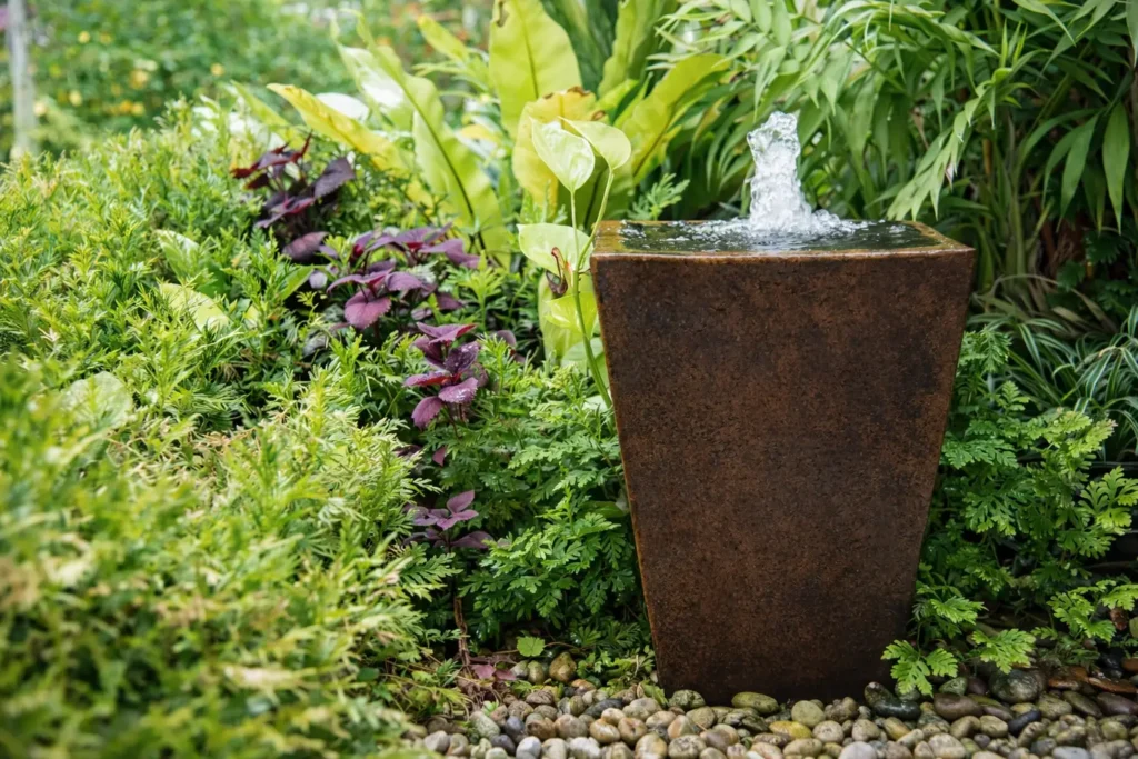 contemporary garden fountain with bubbling water surrounded by lush plants and decorative stones