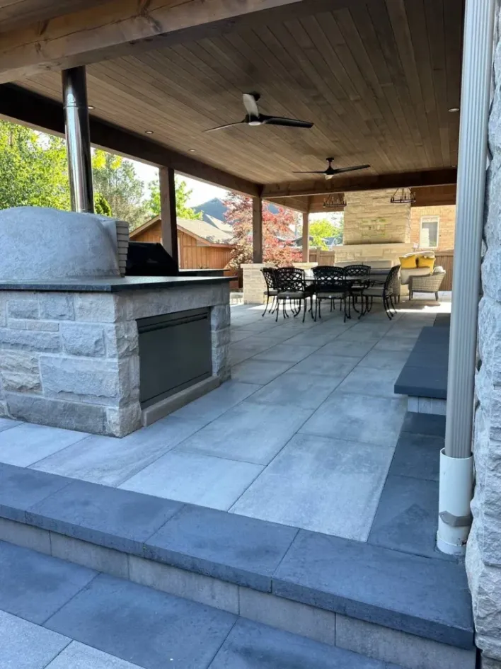 covered patio with outdoor kitchen, stone oven, dining table and seating area