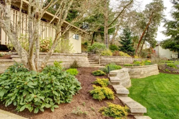 Tiered stone retaining wall with landscaped garden and steps on sloped backyard
