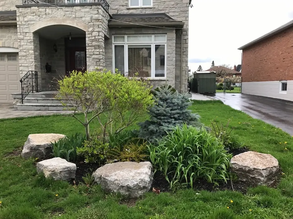 Landscaping with decorative stone border, planted shrubs, and sod, image by OAKS Home Services