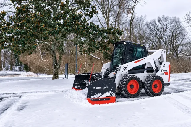 Oaks Bobcat S650 clearing snow in a parking lot, photo by Oaks