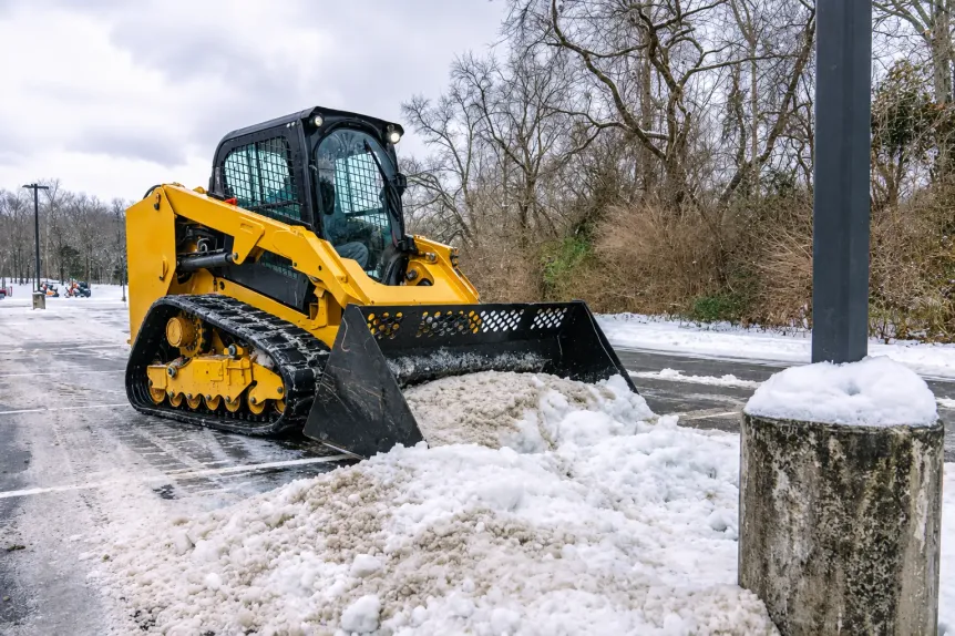 Tracked skid steer clearing snow near a parking lot, photo by Oaks