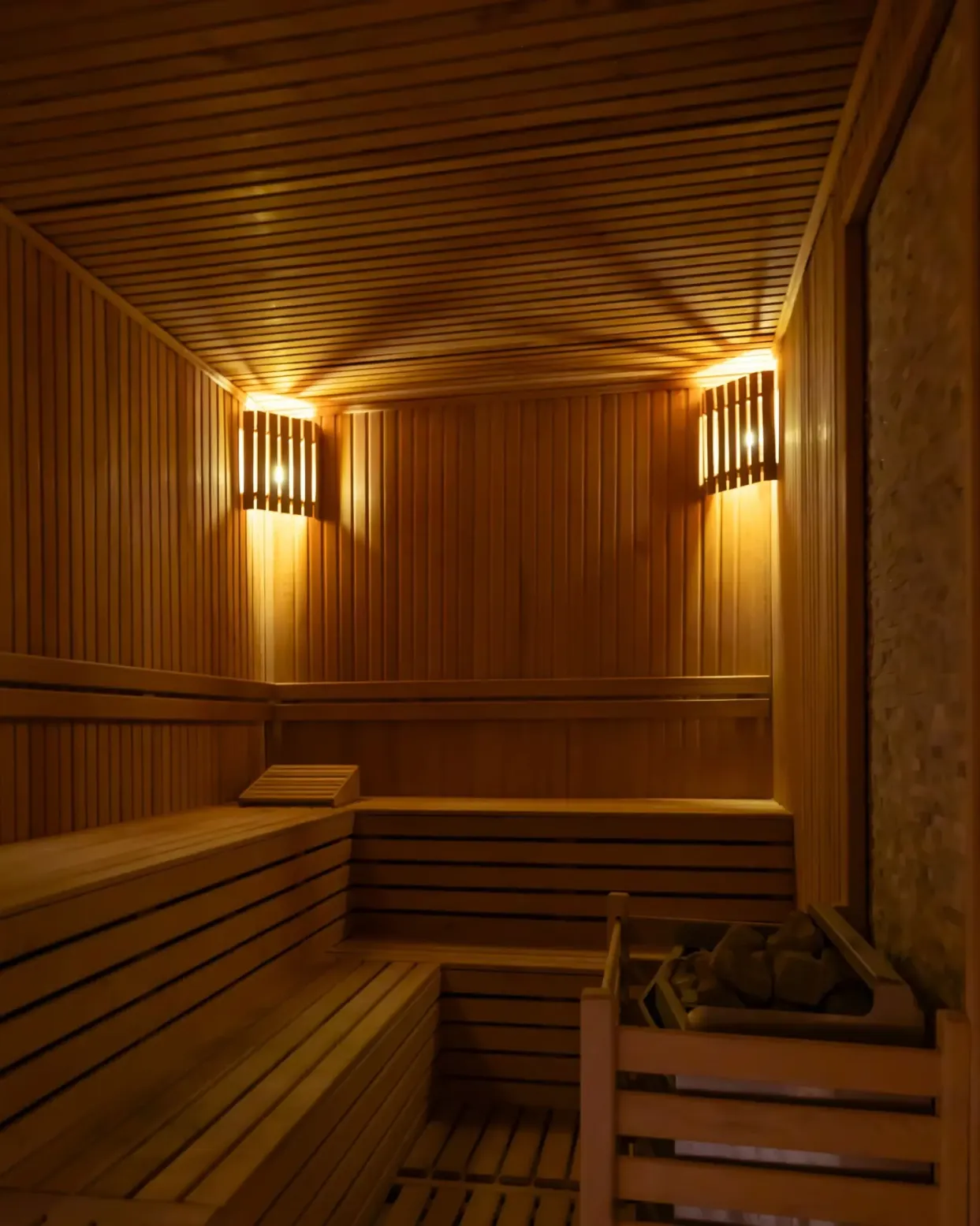 Traditional wood sauna with tiered benches and warm wall lighting, photo by Oaks