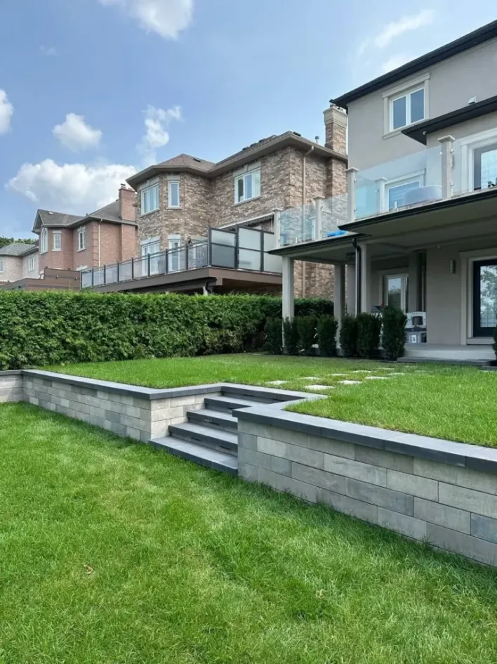 tiered retaining wall with steps creating raised lawn levels in backyard