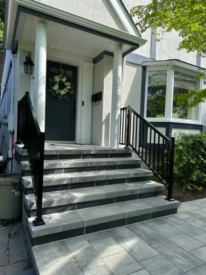 front entrance steps with interlocking stone black railing and clean residential design