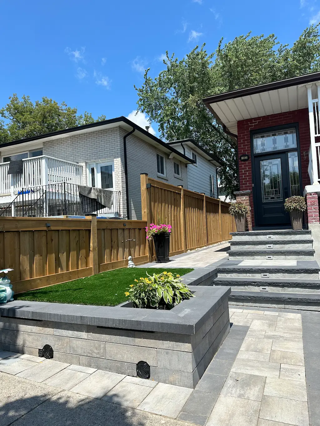 front yard interlocking steps with retaining wall planter and wood privacy fence