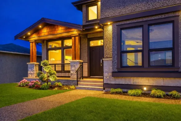 front yard walkway with landscape lighting, lawn and illuminated house entrance at night