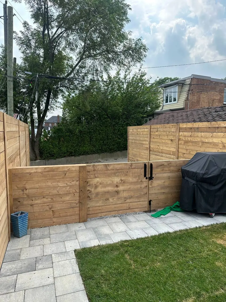 horizontal wood privacy fence with double gate and black hardware in backyard