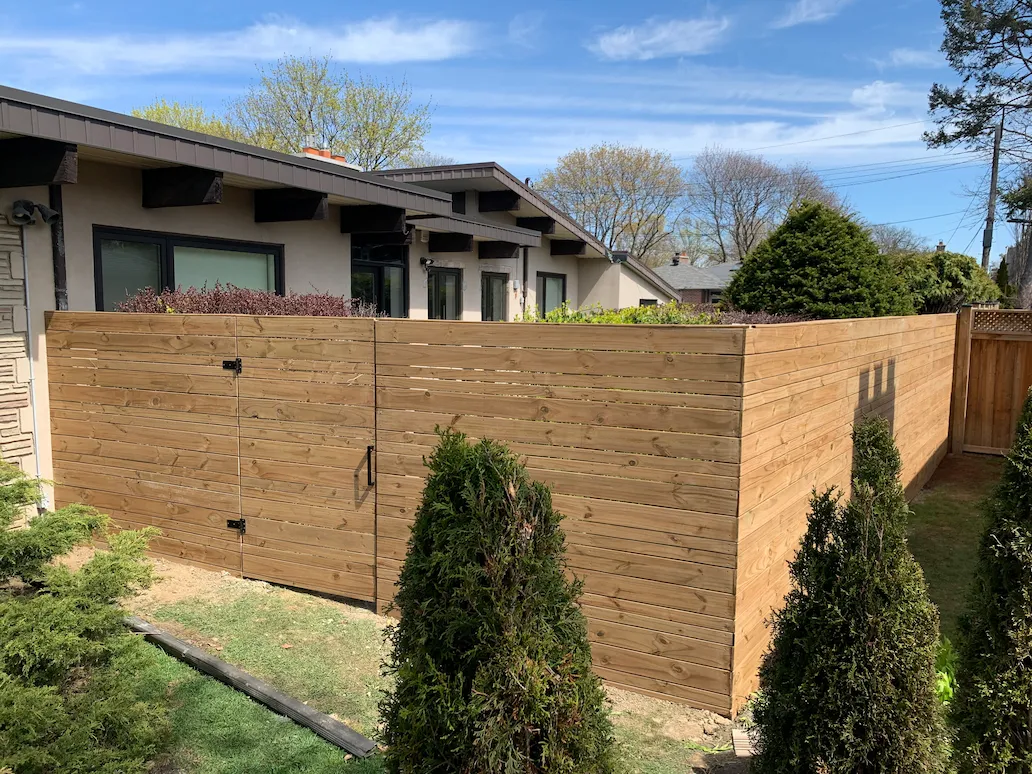 horizontal wood privacy fence enclosure with single gate around backyard space
