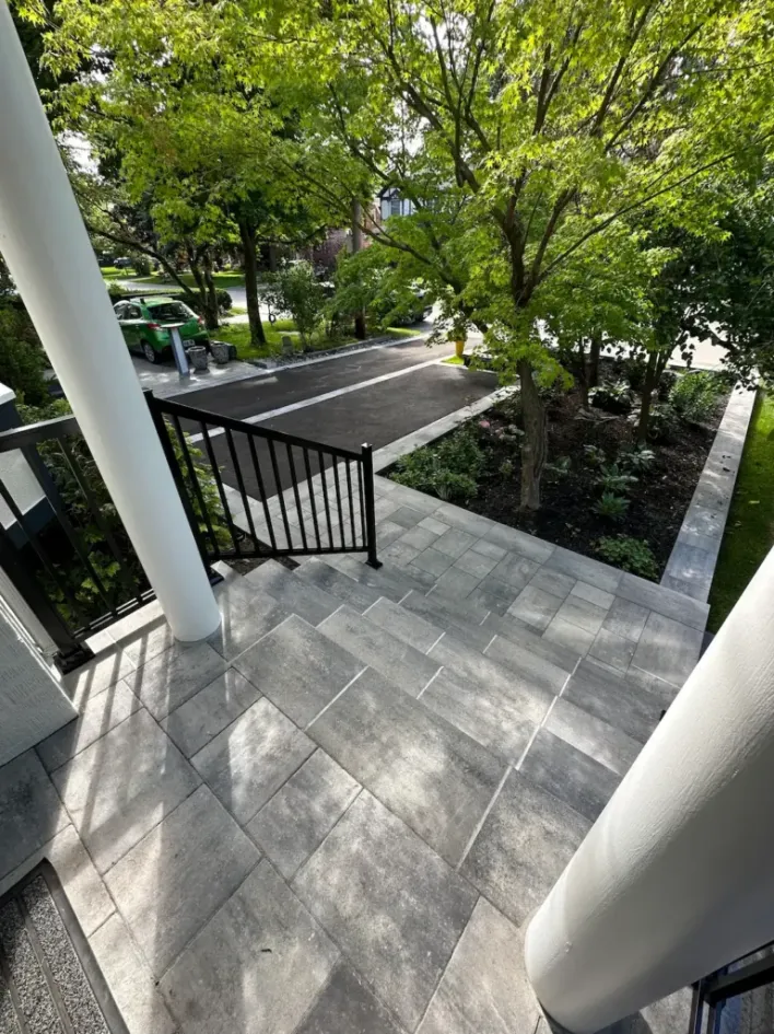 interlocking stone front steps with railing landscaped garden and residential driveway view