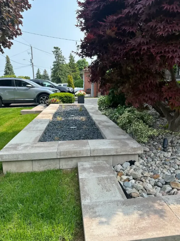 modern raised concrete planter with decorative stone and landscaping in front yard