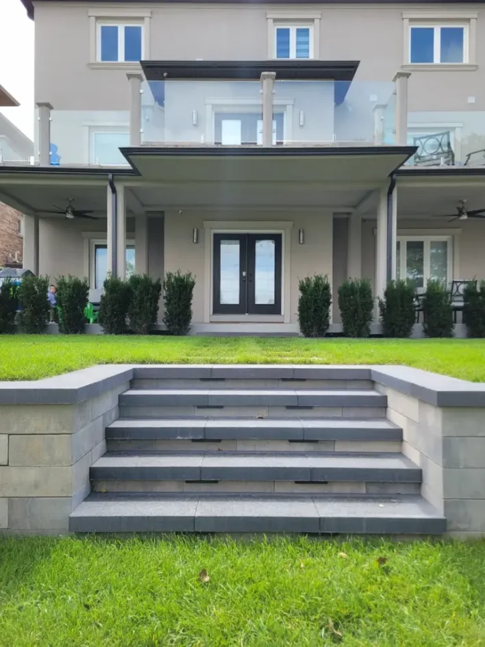retaining wall with wide steps leading to raised backyard lawn and patio