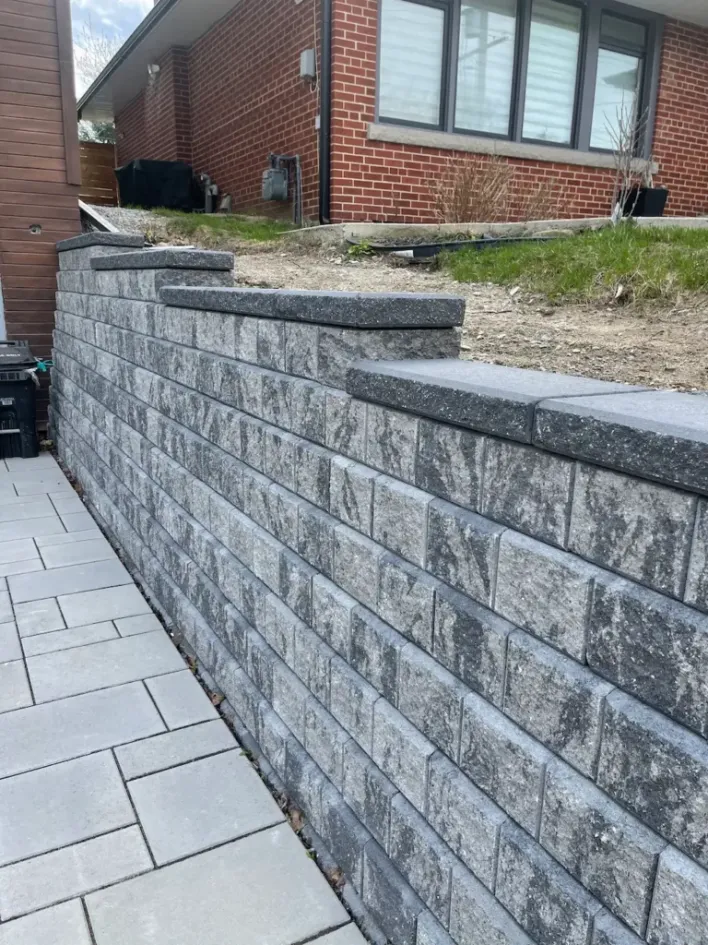 tiered retaining wall with interlocking concrete blocks along backyard walkway