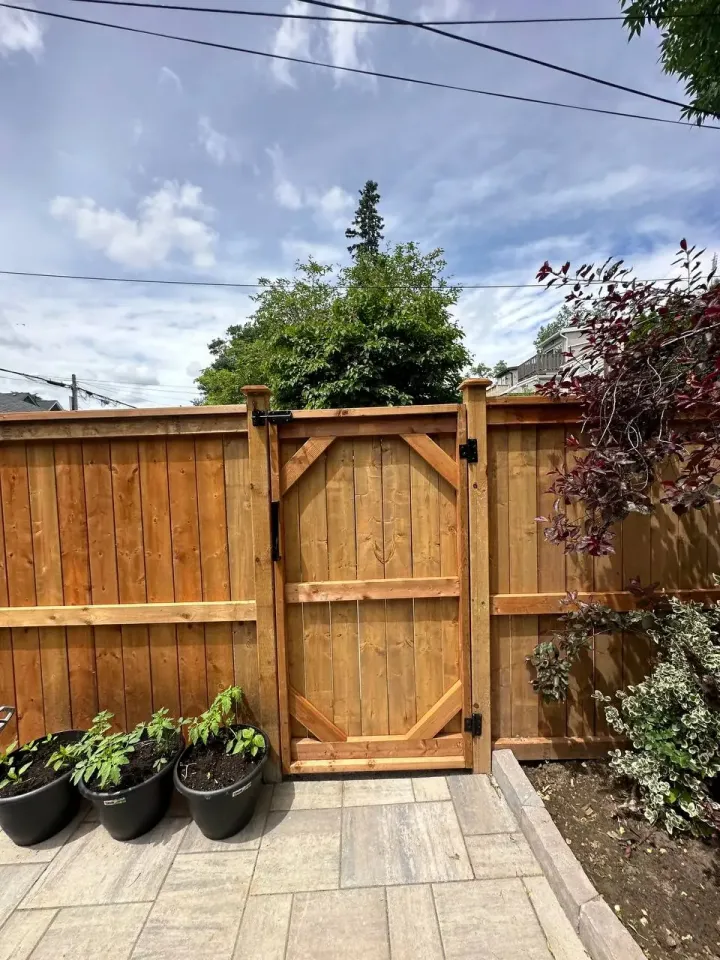 wood privacy fence gate with black metal hinges and latch on backyard patio