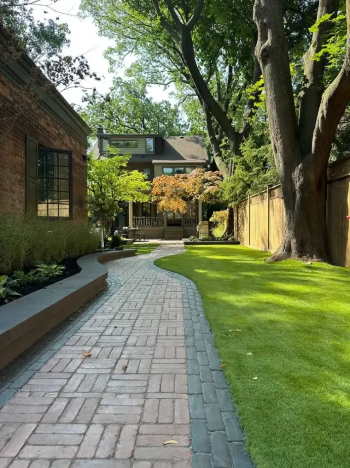 curved interlocking paver walkway with lawn and garden leading through landscaped backyard