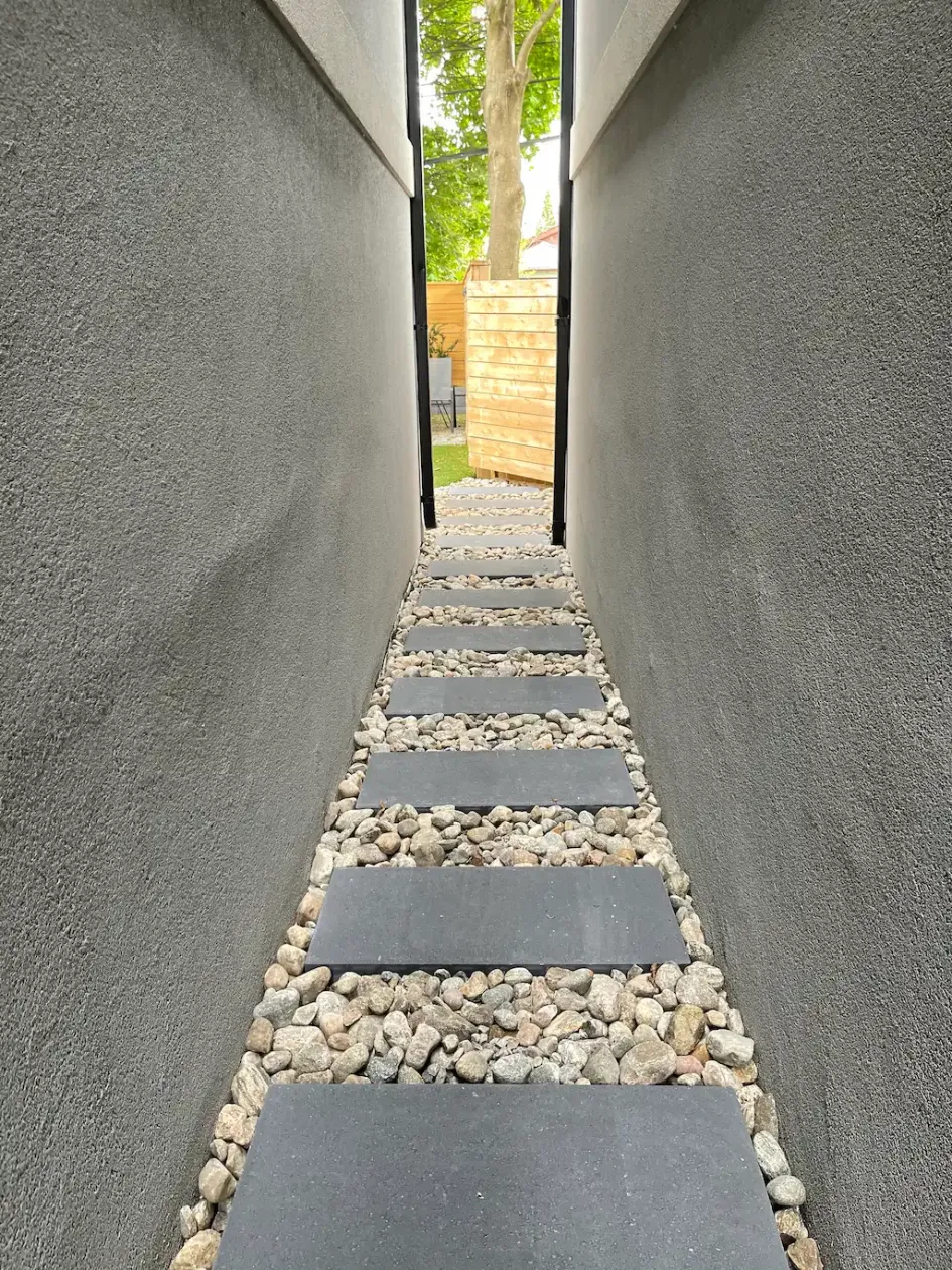 side yard pathway with stepping stones set in gravel between two house walls