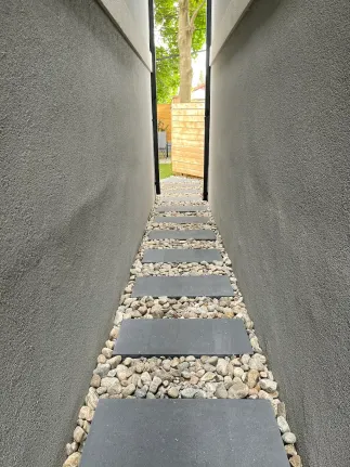 side yard pathway with stepping stones set in gravel between two house walls