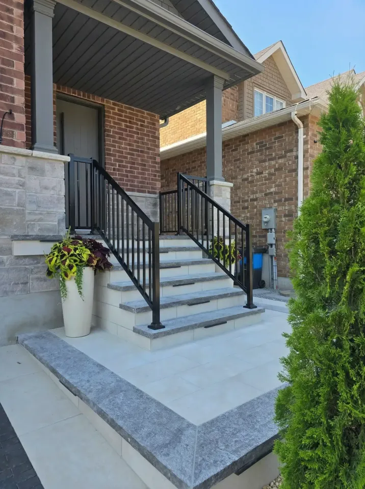 front porch with interlocking steps and modern railing leading to house entrance