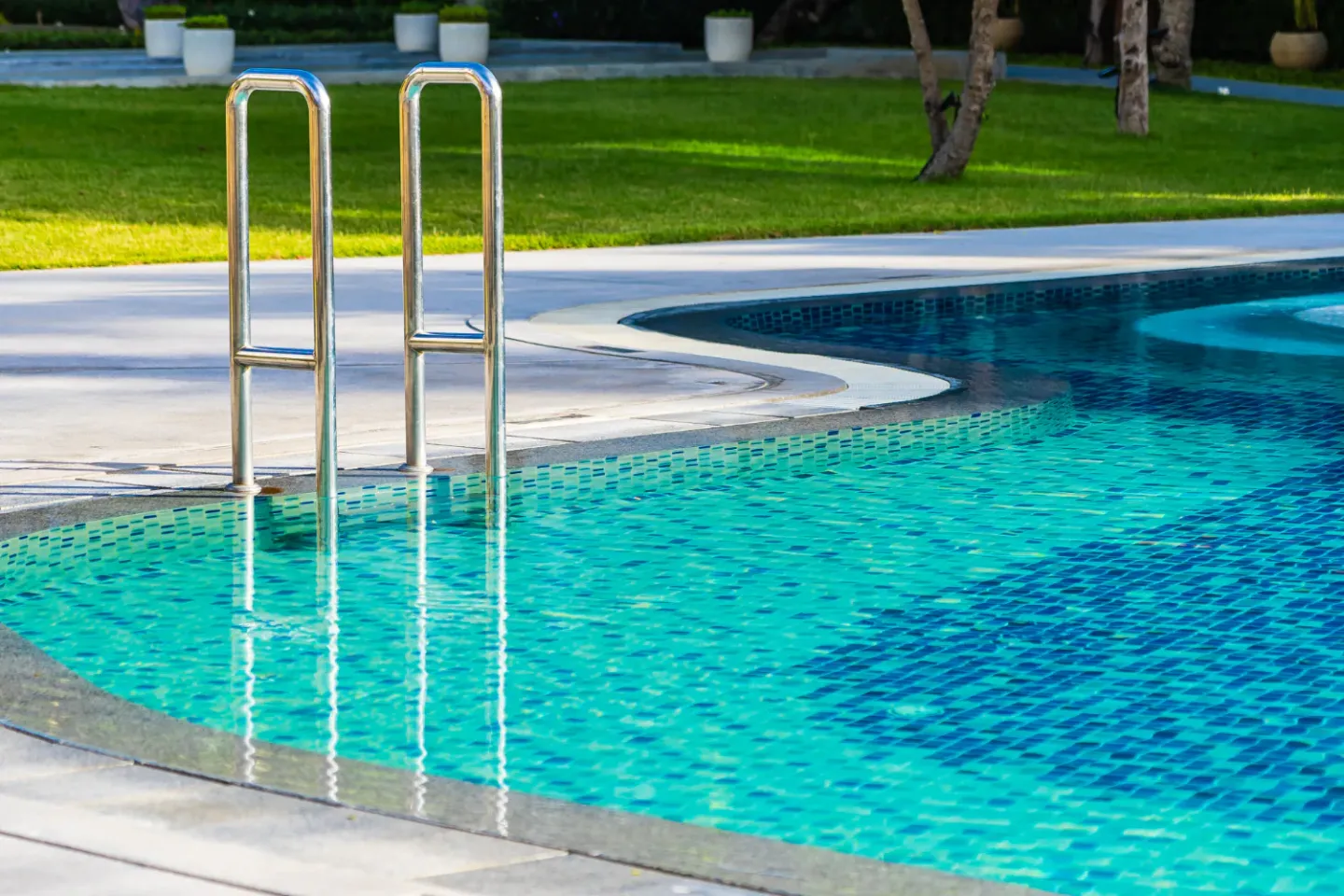curved swimming pool edge with metal ladder, blue mosaic tiles, and clean modern poolside design
