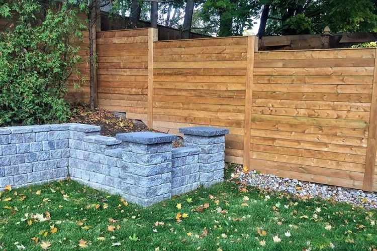 Retaining wall corner with concrete blocks and horizontal wooden privacy fence installation