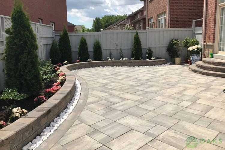 Curved retaining wall with interlocking stone patio and landscaped backyard design