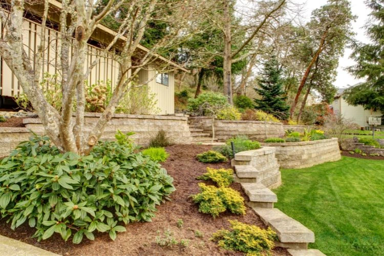 Tiered stone retaining wall with landscaped garden and steps on sloped backyard