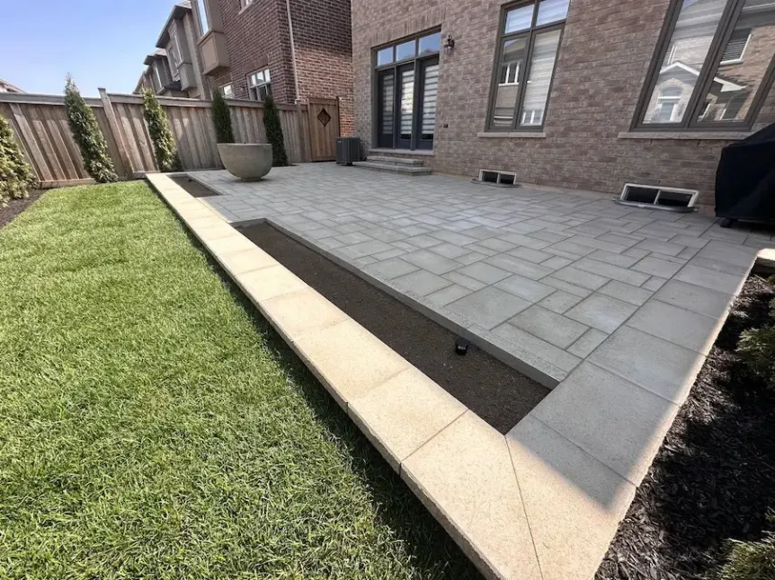 Modern interlocking stone patio with raised border and clean edge detailing in Toronto backyard