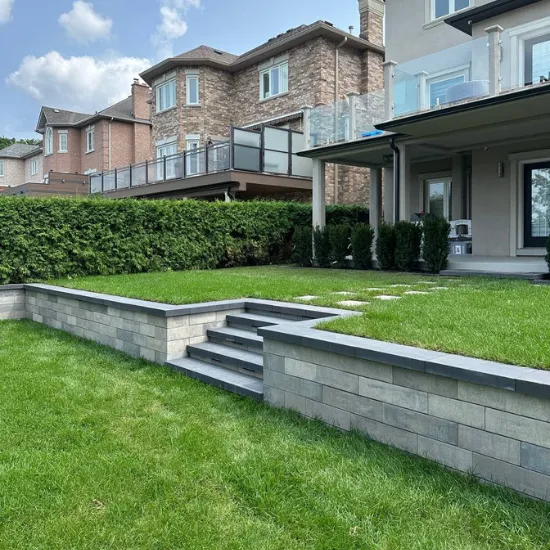 Backyard retaining wall with concrete steps and raised lawn terrace behind a residential home, image by OAKS Home Services