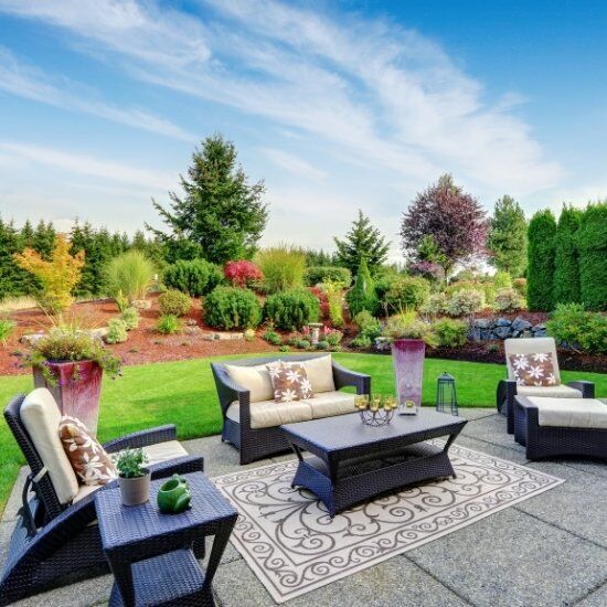 Outdoor patio seating with paved terrace overlooking a landscaped garden and lawn