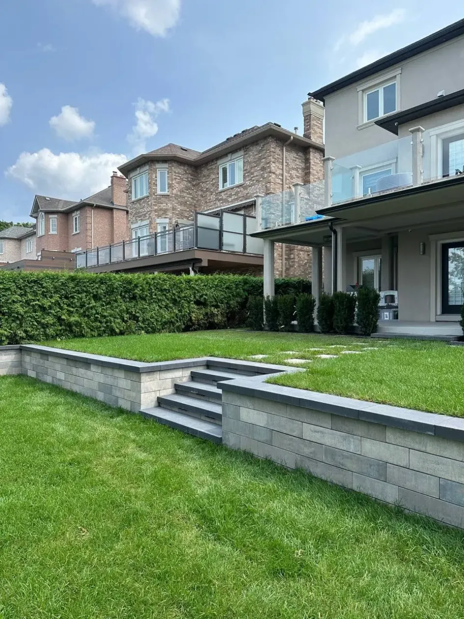 tiered retaining wall with steps creating raised lawn levels in backyard