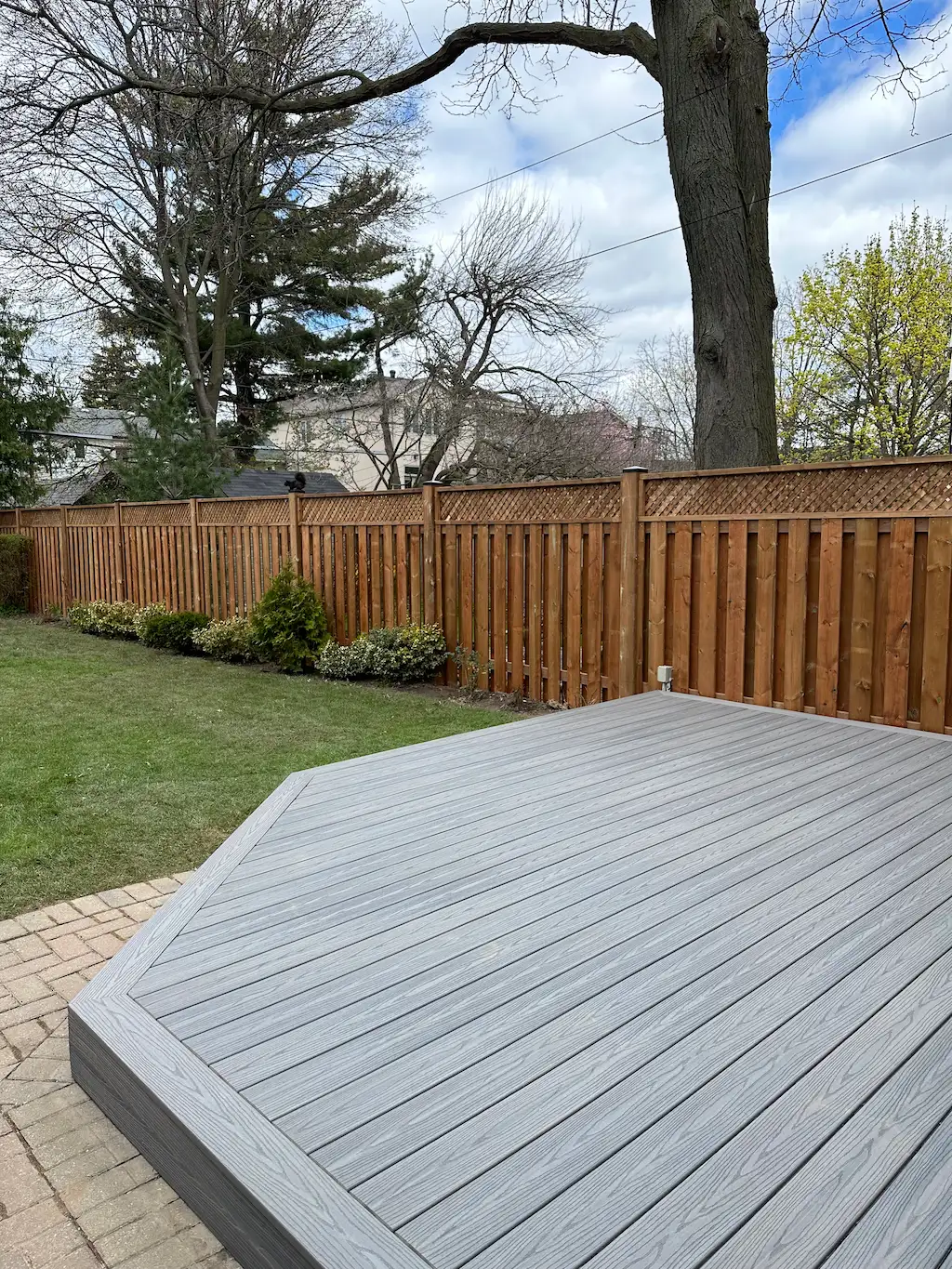 composite deck platform in backyard with wooden fence and landscaped lawn