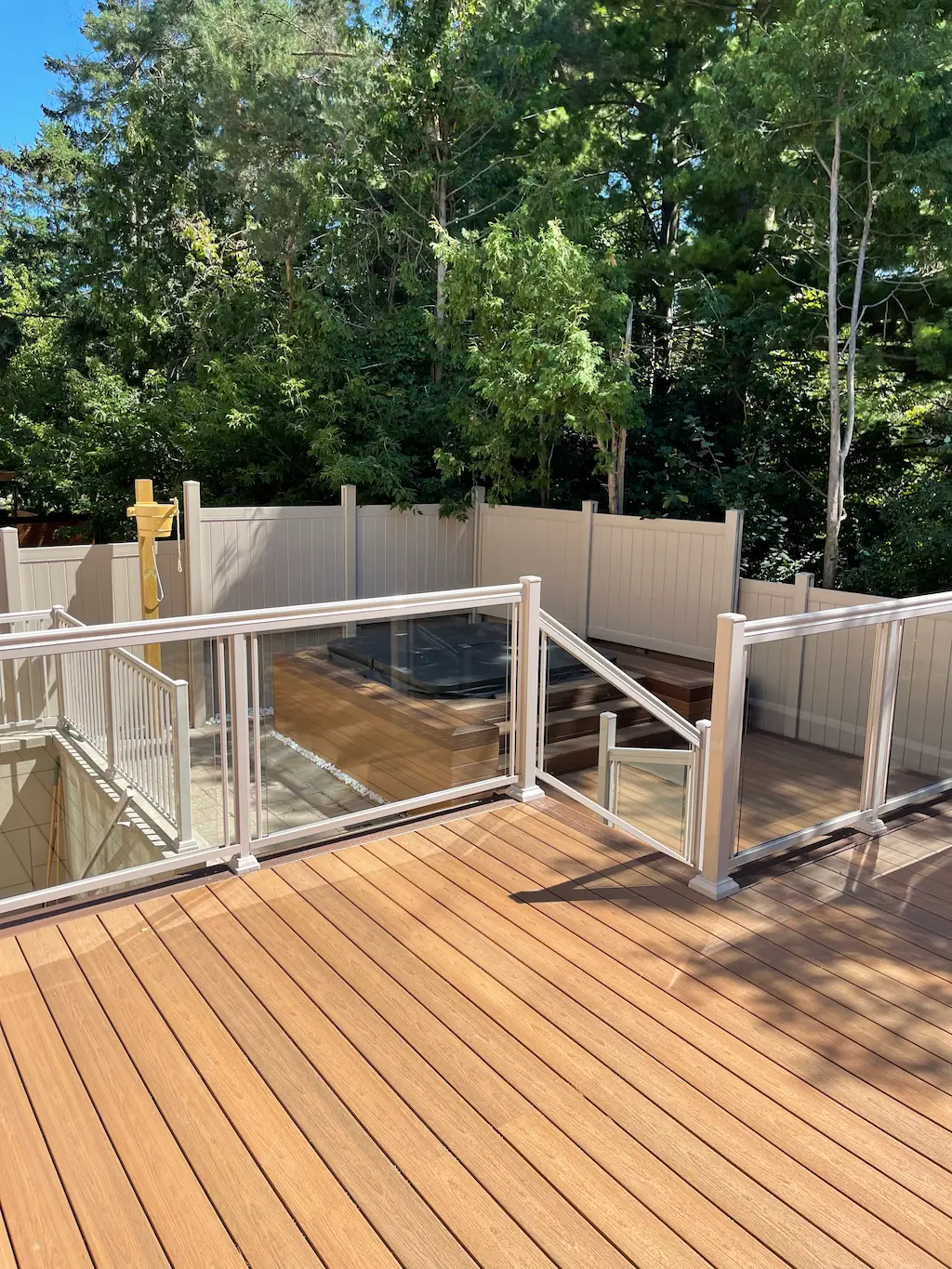 multi level wood deck with glass railing and built-in hot tub area in backyard