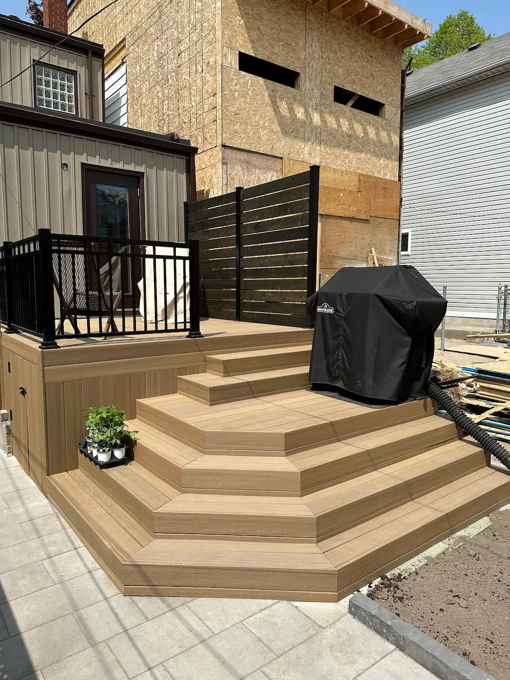 multi level wood deck steps with seating area and black railing in backyard patio