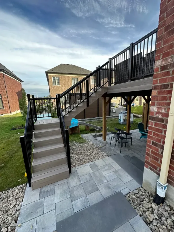 raised composite deck with stairs and interlocking patio seating area underneath