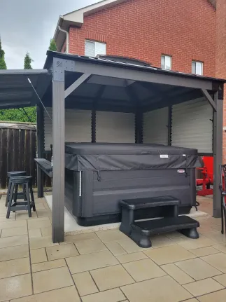 covered pergola over backyard hot tub spa area with privacy panels and seating