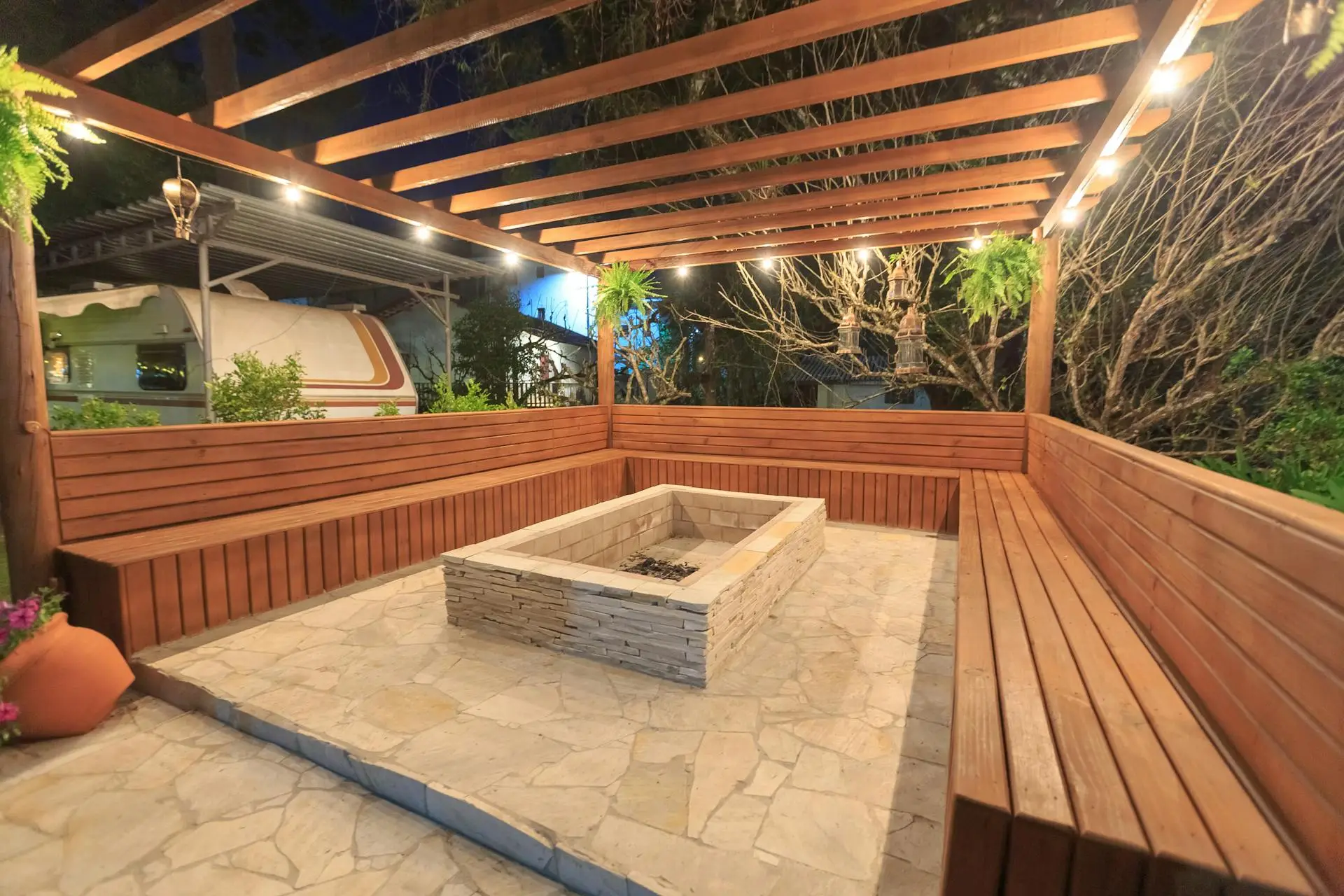 covered pergola patio with built in wooden bench seating and central stone fire pit