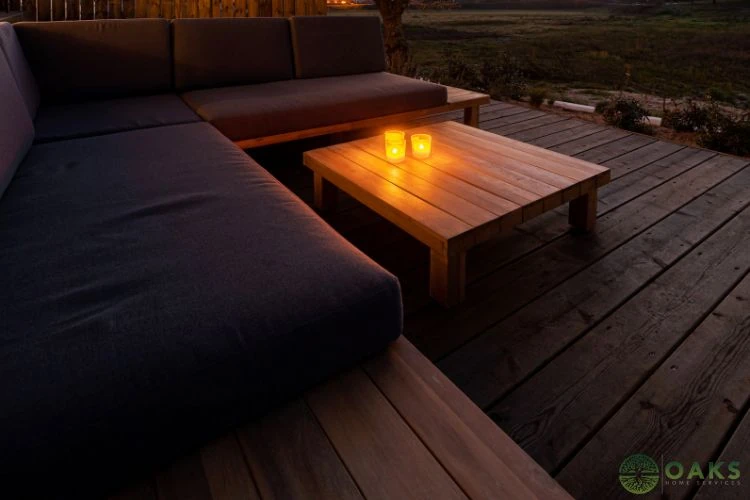 Built-in deck seating with outdoor sofa and wooden table on backyard deck at night