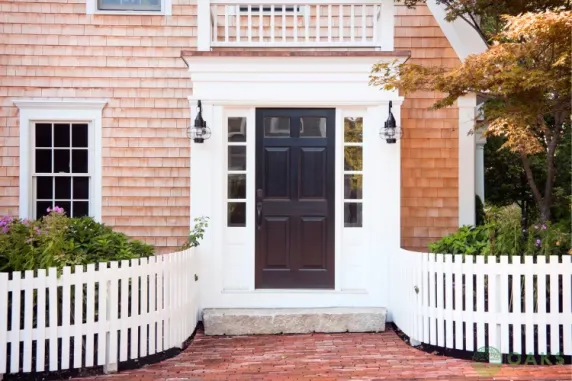 White picket fence and brick walkway leading to front entrance of traditional home