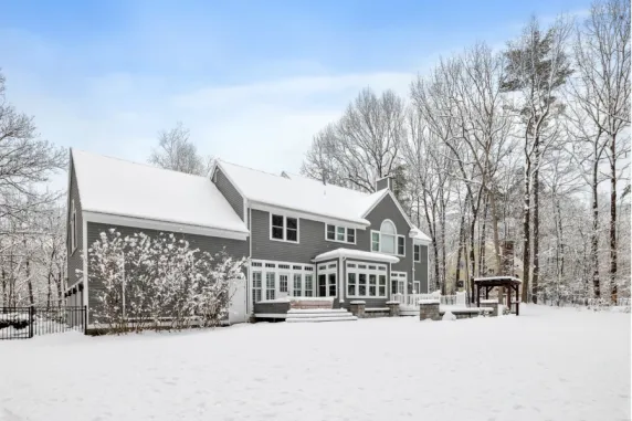 Snow-covered backyard and landscaping around residential home during harsh winter weather