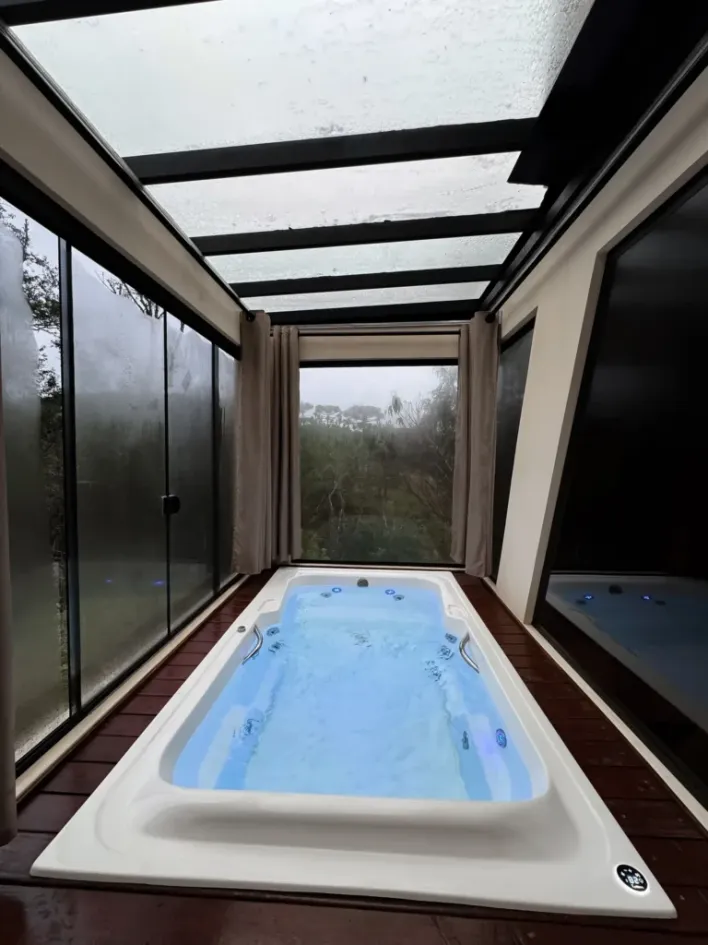 Indoor jetted hot tub in a glass enclosure with a forest view, photo by oakshs.ca