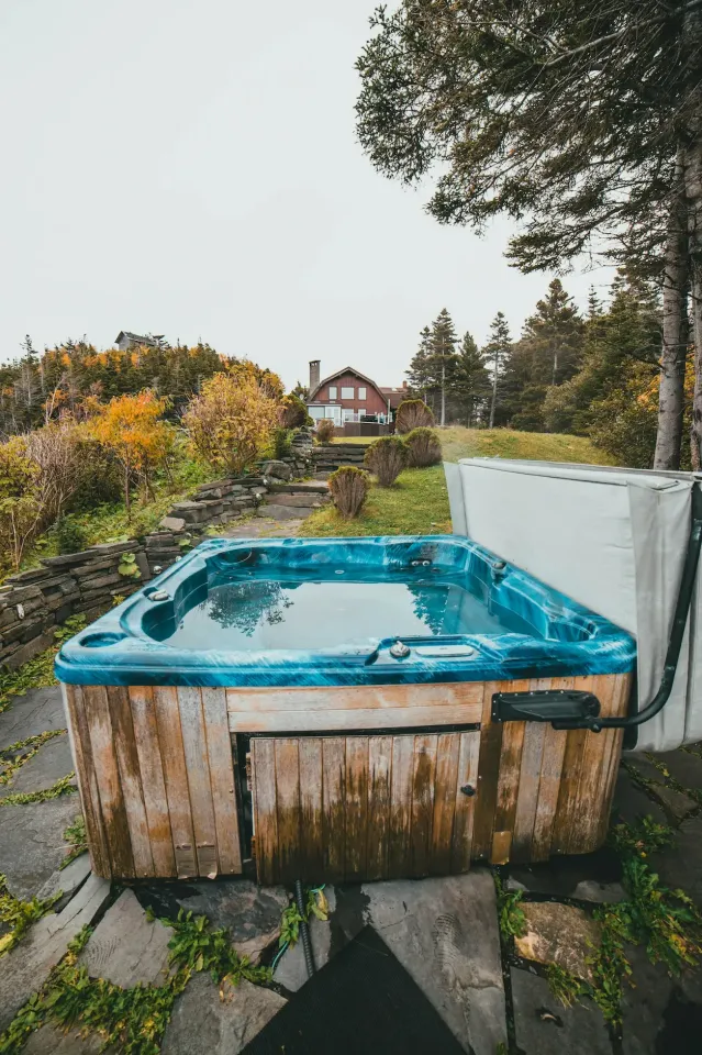 Outdoor hot tub with wood cabinet on a stone patio in an autumn backyard, photo by oakshs.ca